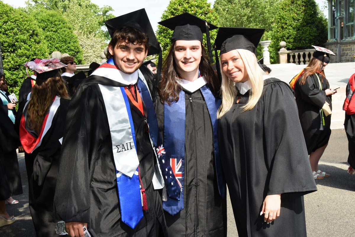 Three students smiling during the graduation ceremony on Haber Green