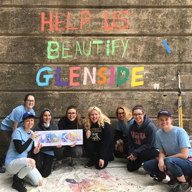 Students crouching in front of wall that says "Help Us Beautify Glenside"