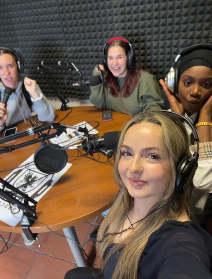 Sophie and other students sitting around a table recording a podcast.