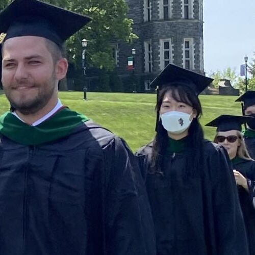 Students wearing black cap and gowns forming a line as they walk down in their graduation