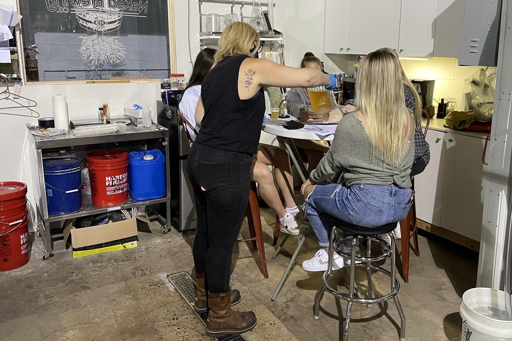 A group of women with one pouring a beer for them all