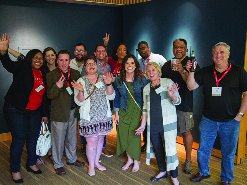 A group of people celebrating an event smiling into the camera
