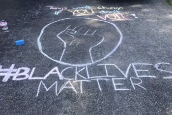 Black Lives Matter with hashtag and encouragement to vote drawn in chalk on a driveway