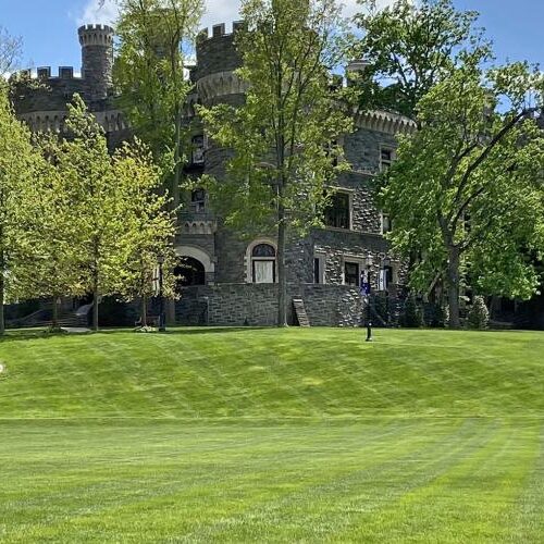 Two dozen flags from different countries stand on Haber Green with Grey Towers Castle in the background