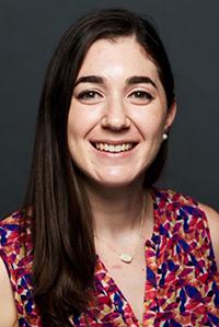 The headshot of a woman in a short sleeve floral pattern blouse