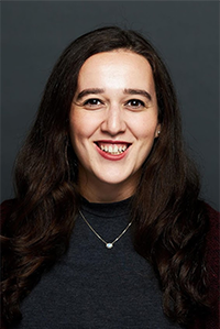 The headshot of a woman in a long sleeved dark green shirt