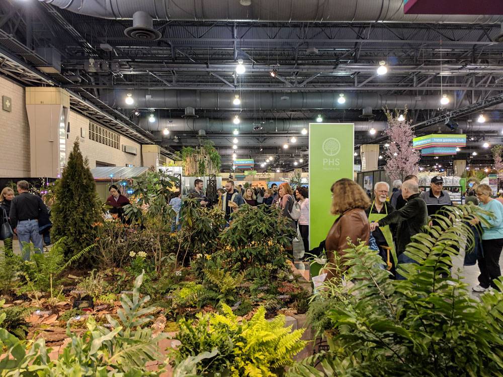 An exhibition resembling the ground of a forest with people walking by it.