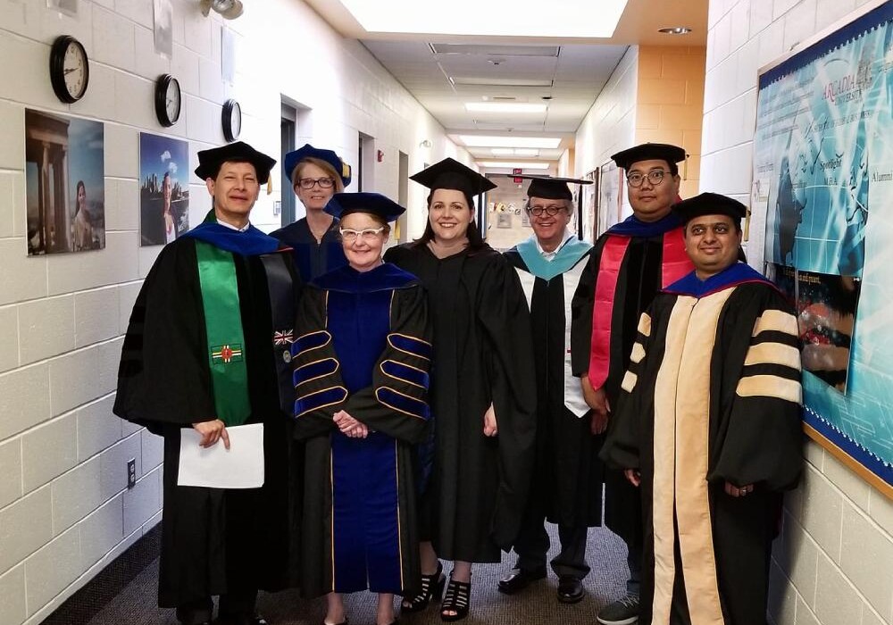 SGB Faculty standing in caps and gowns in hallway