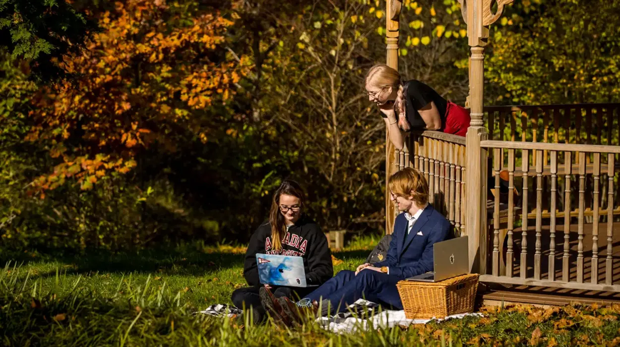 Three students outside working on laptops