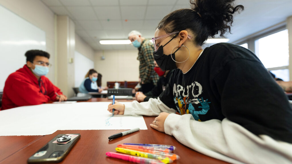 Student writes on a large piece of paper.