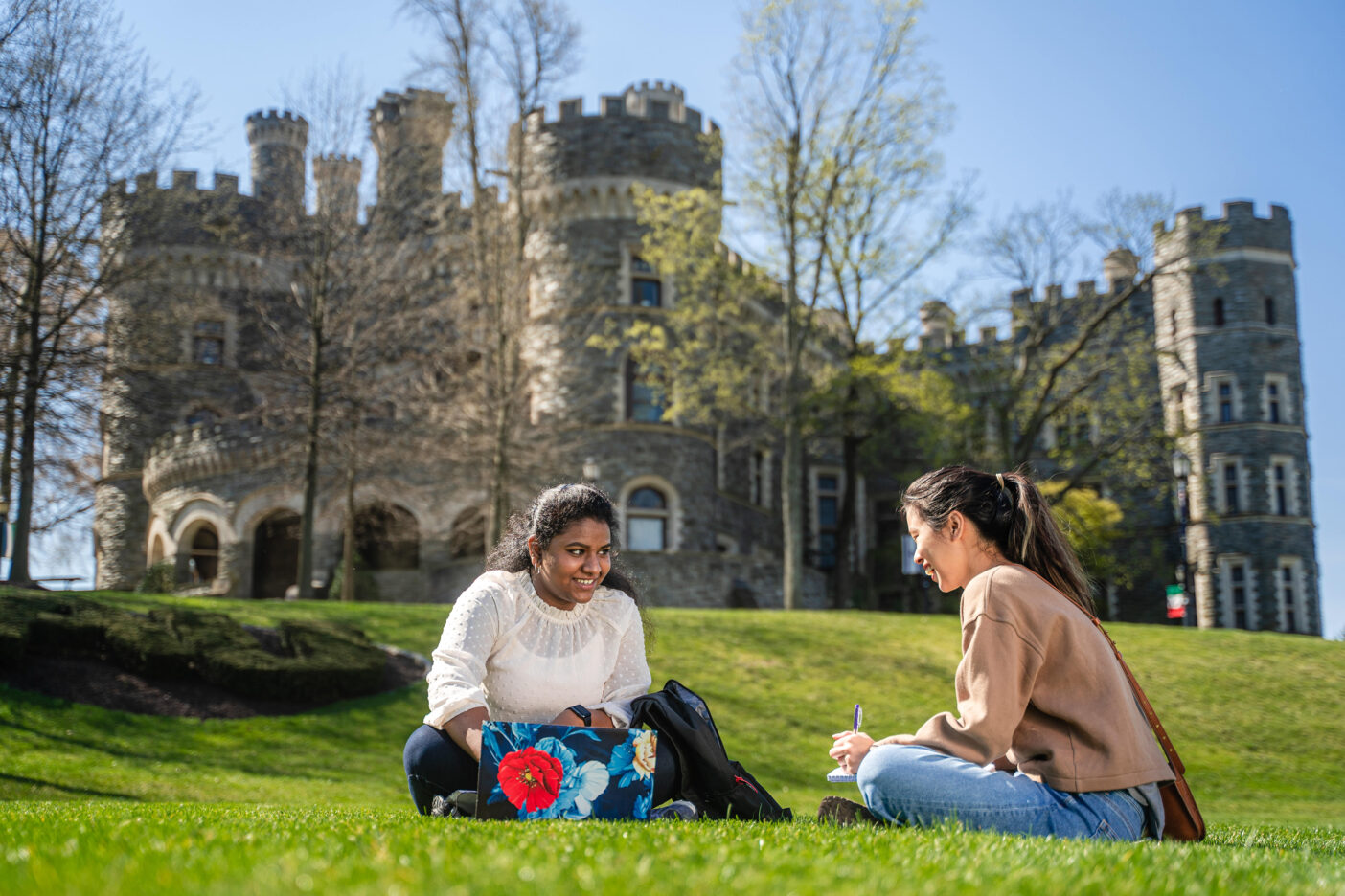 Arcadia University students sit on the lawn by Grey Towers