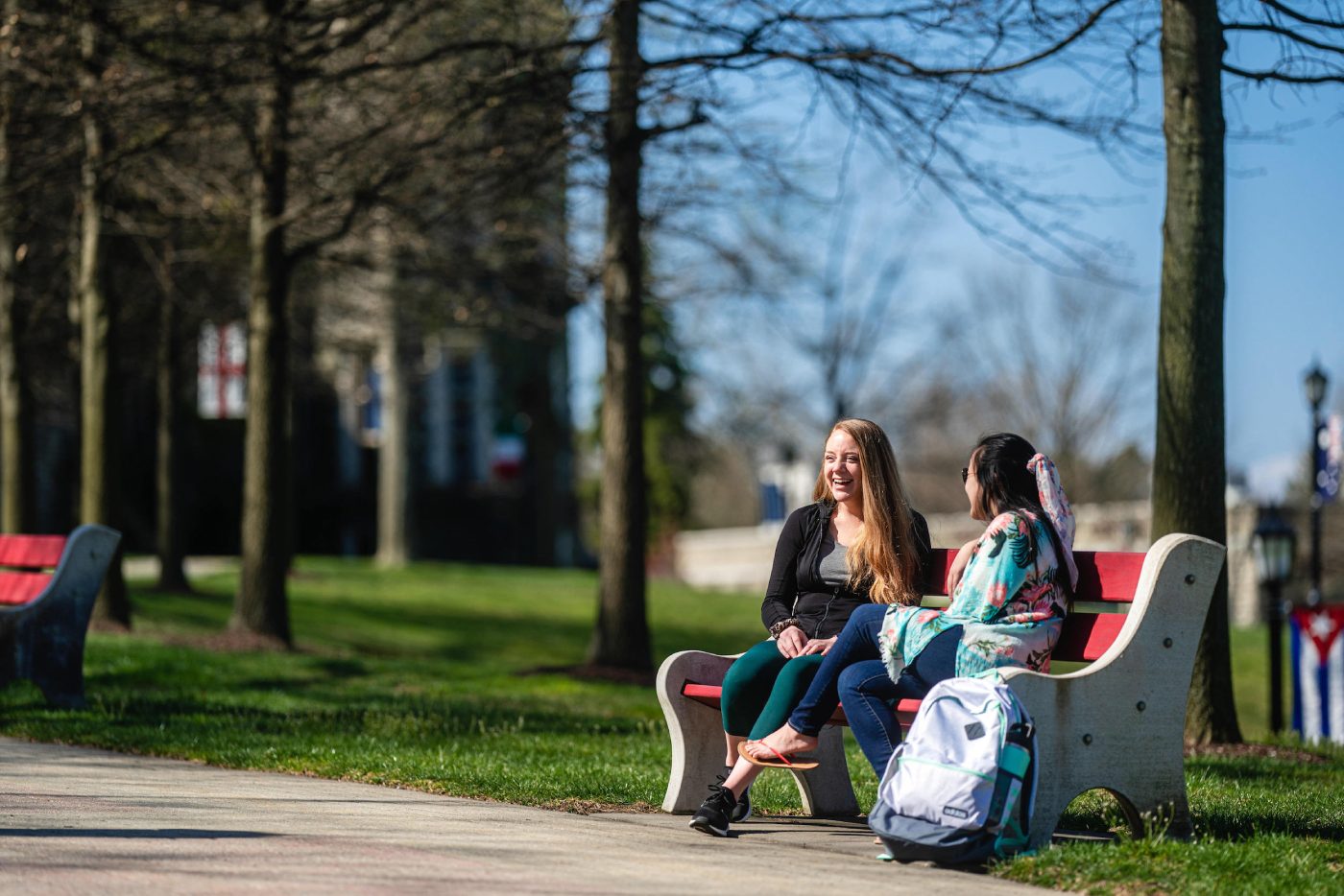 Two undergraduate admissions to Arcadia University students enjoy time outside on campus bench.