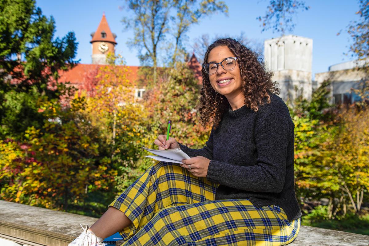 College student sitting outside on holding writing in notebook 