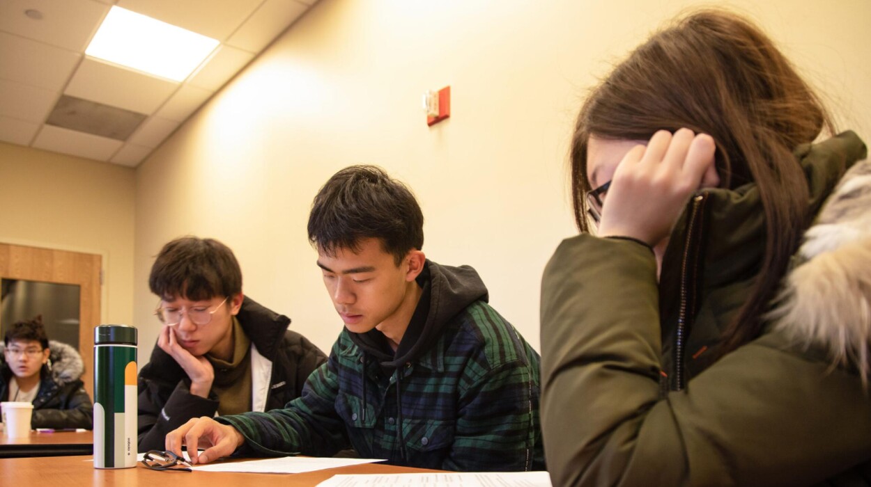 International students work on paperwork in a classroom.