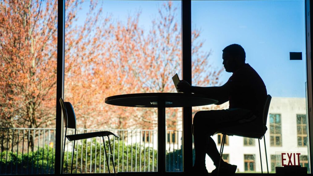 Silhouette of a student sitting at a table in Stein Fireplace Lounge.