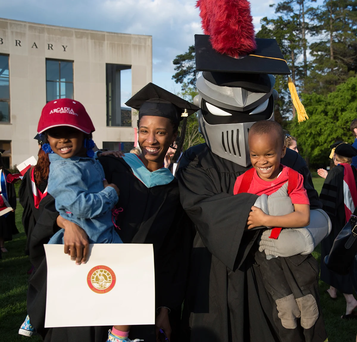 Graduating student posing with her children and Archie, the mascot.