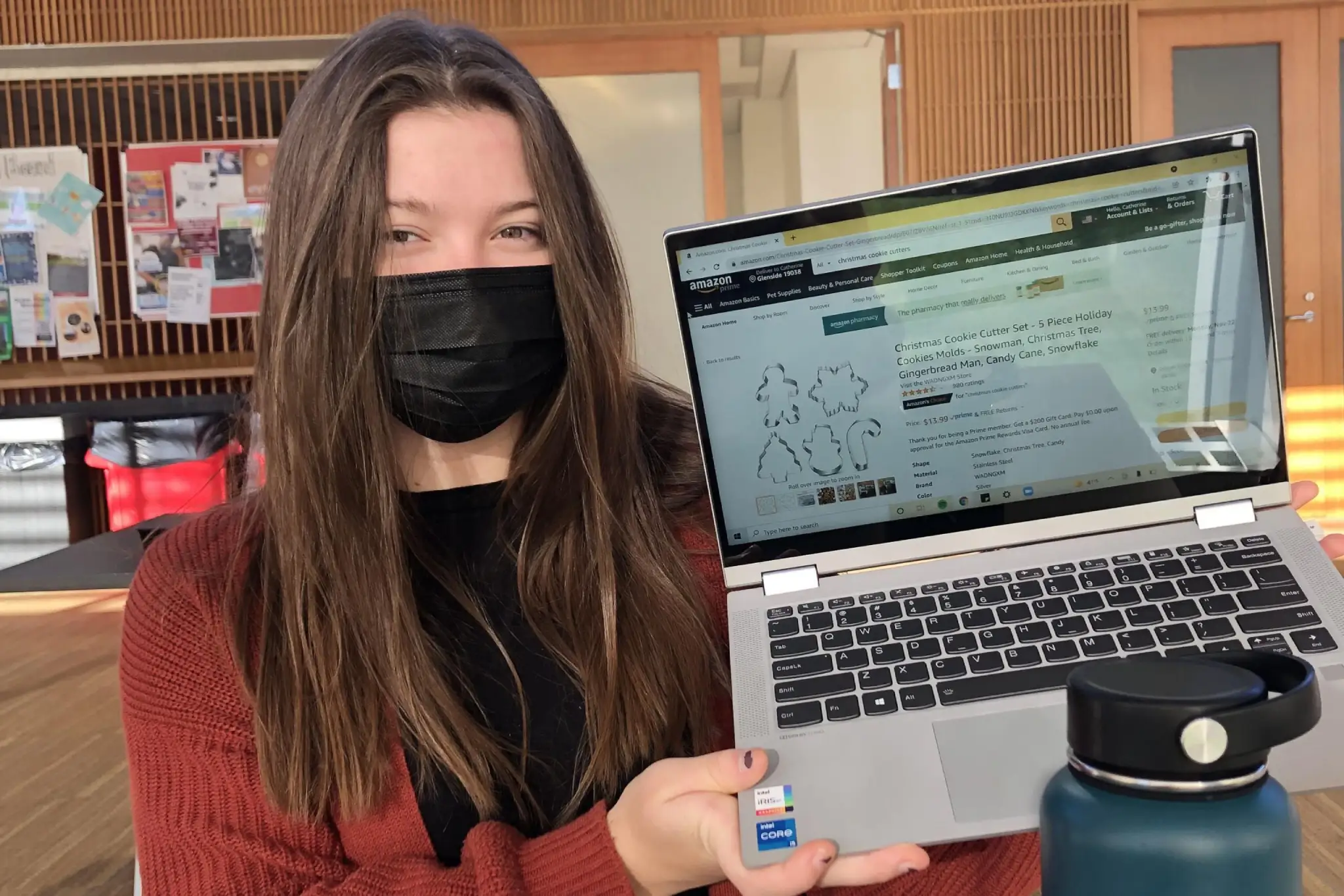 Student in face mask holding up laptop with internet browser open