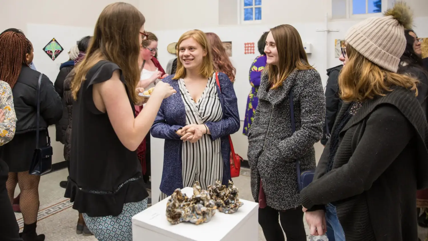 Art gallery exhibit in Murphy Hall with a crowd of students mingling and observing art