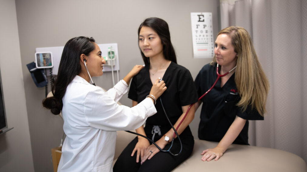 Physicians Assistant graduate students look at a patient.
