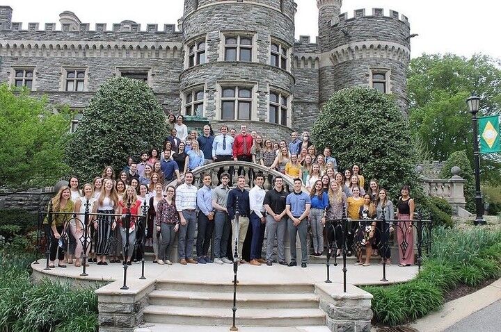 A graduation class of DPT students poses in front of Gray Towers.