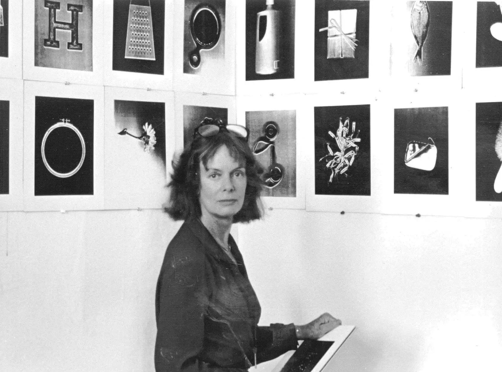 Pati Hill stands in front of a wall of her artwork.