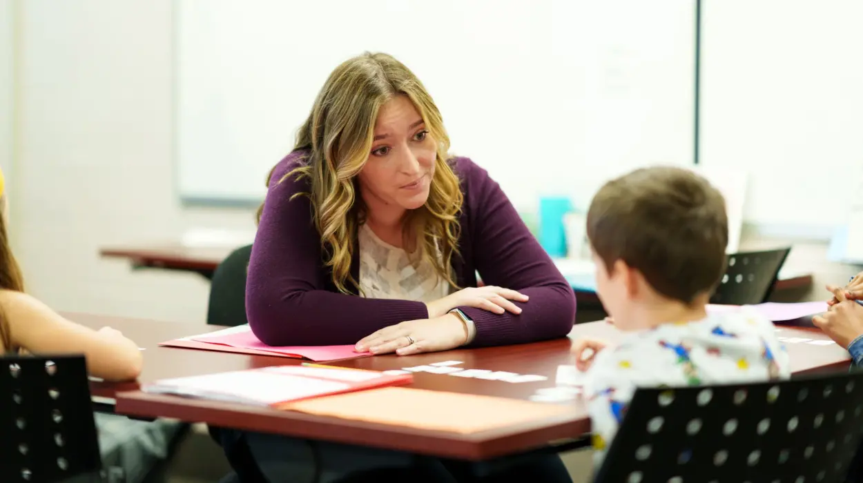 A student teacher helps a student learn reading skills.