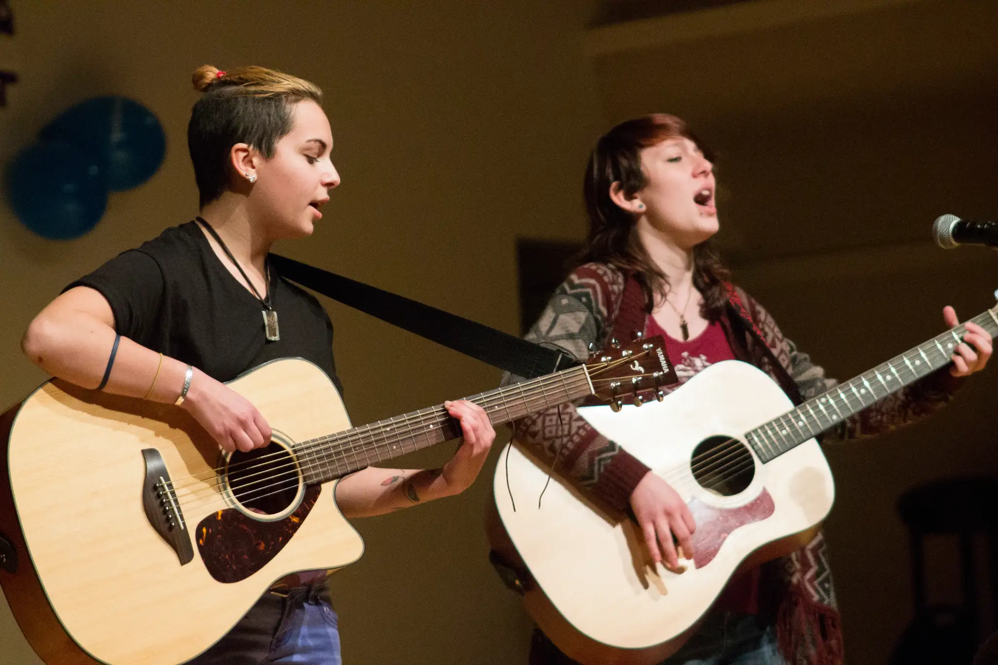 Two students play acoustic guitar and sing