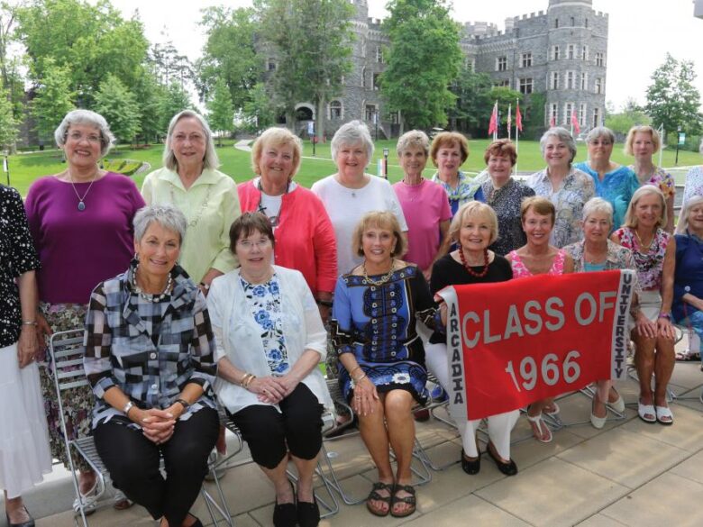 Members of the Arcadia Class of 1966 smile at the camera wholing up a banner that reads "Class of 1966."