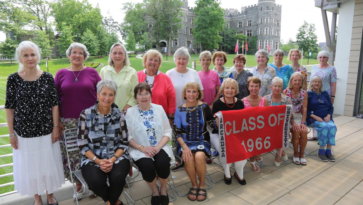 Members of the Arcadia Class of 1966 smile at the camera wholing up a banner that reads "Class of 1966."