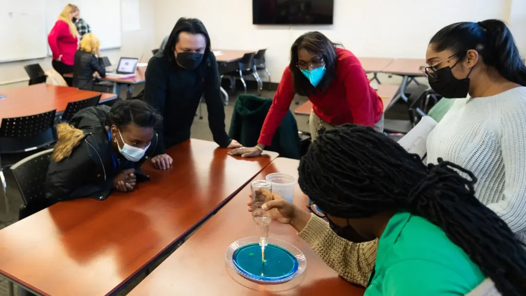 Students work on a STEM teaching experiment with their professor.