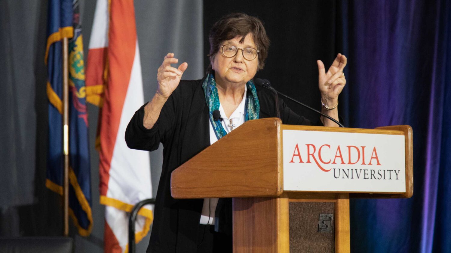 Sister Helen Prejean stands at podium while talking to an audience.