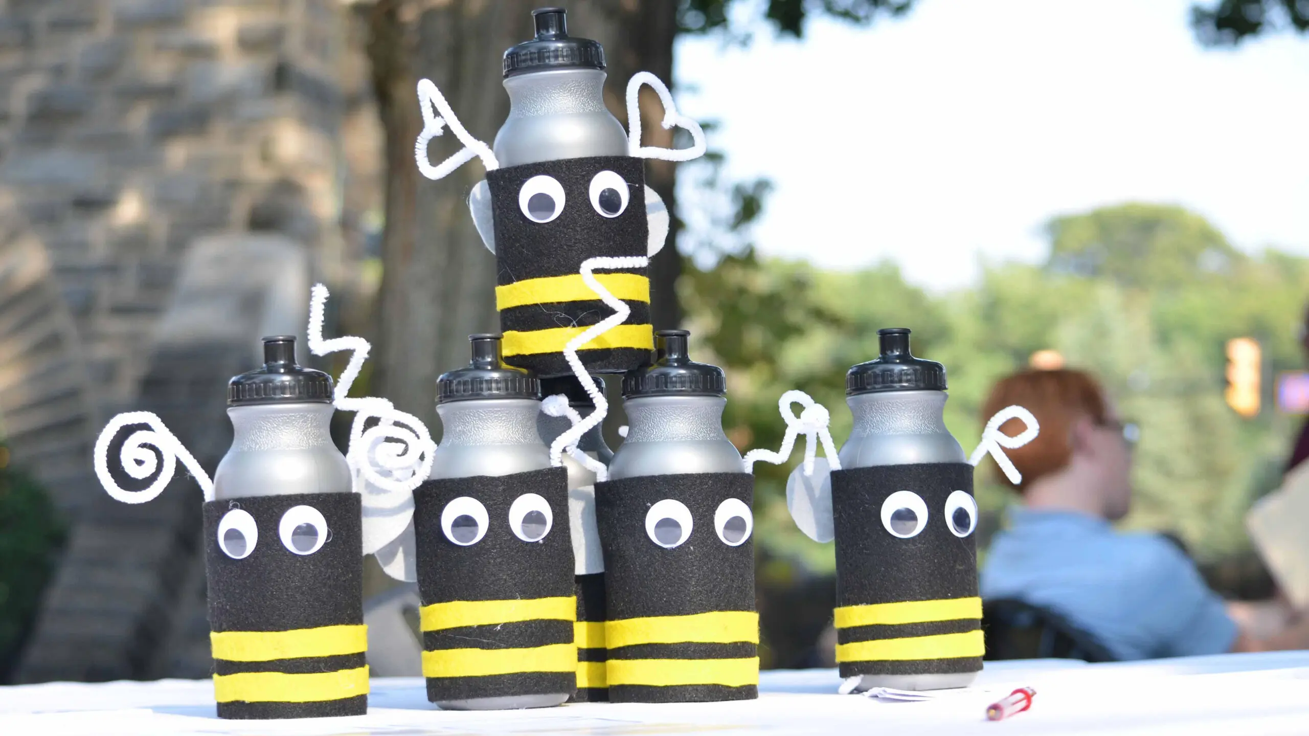 A stack of gray water bottles decorated like bees.
