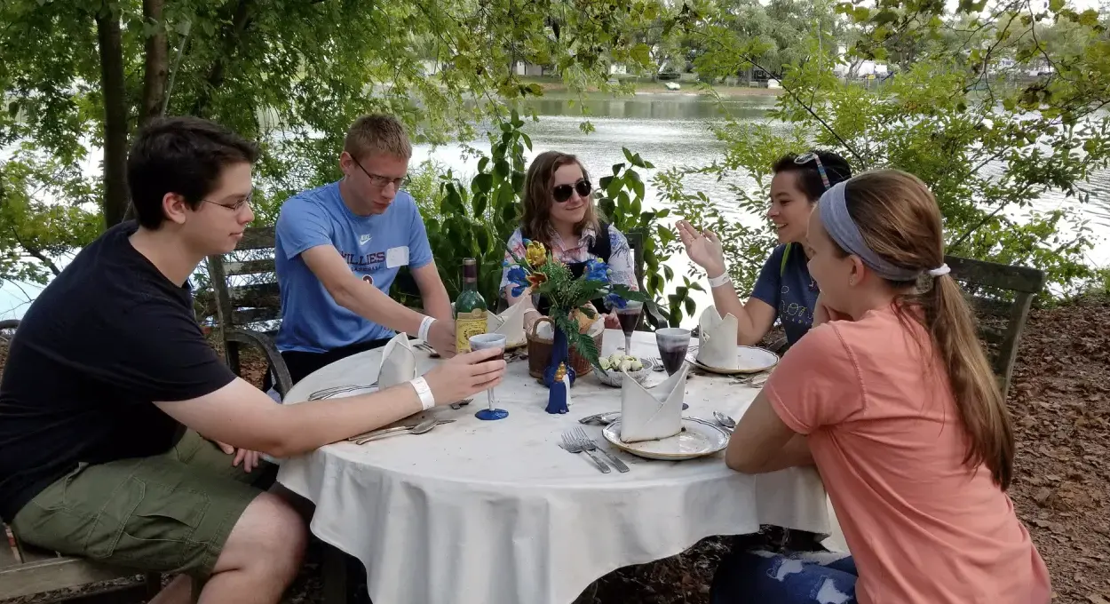 Honors Students talking at a table in front of a lake.