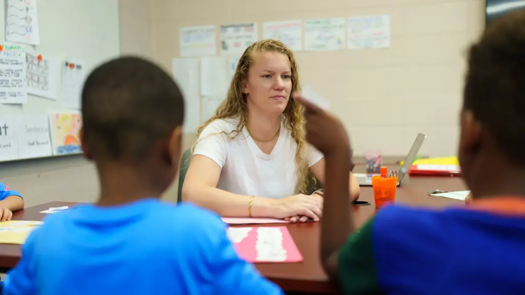 A graduate student works with students on reading skills.