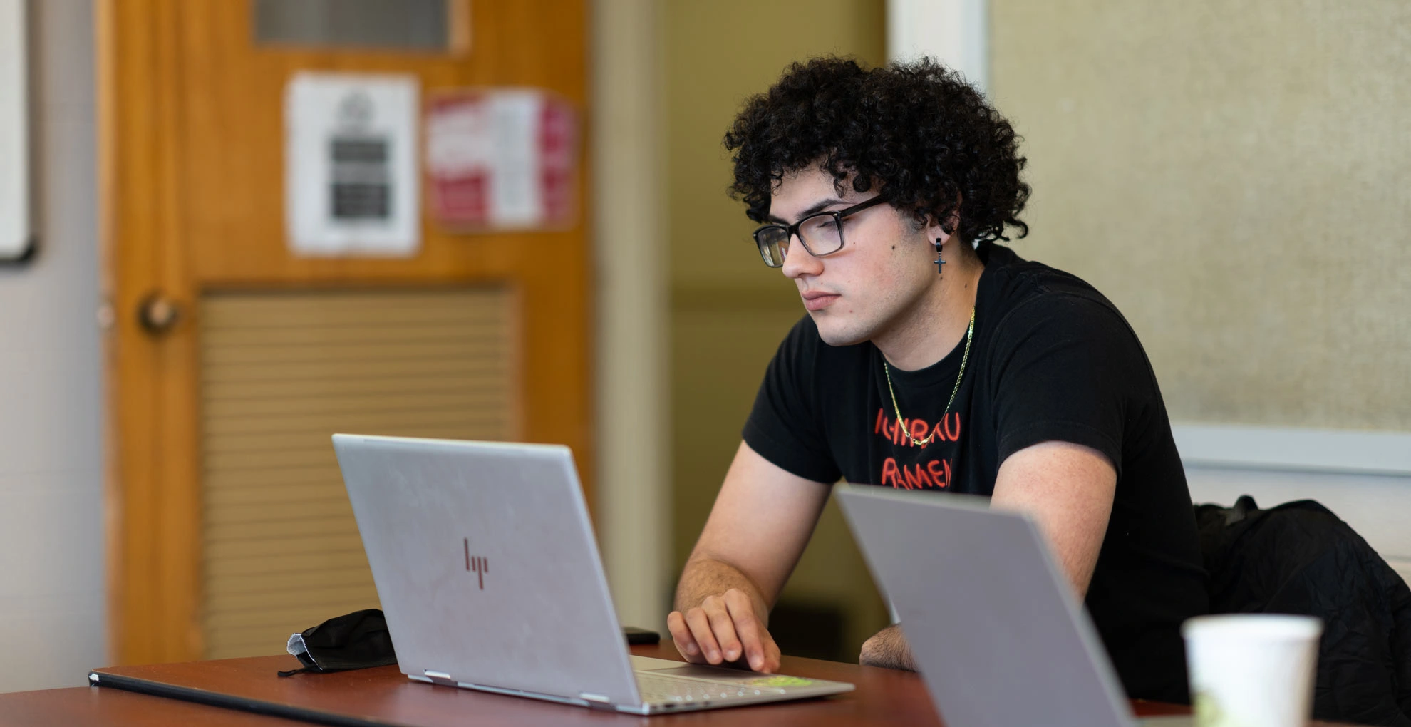 A student works on a laptop in a classroom.