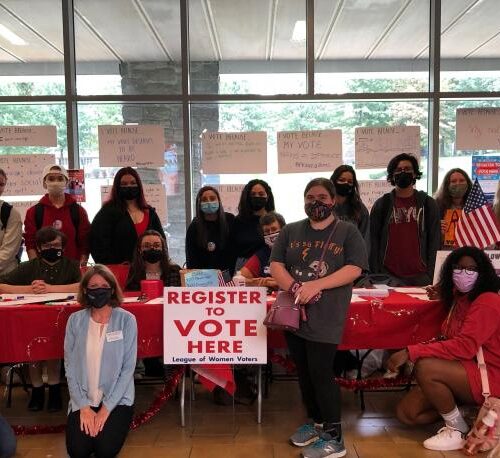 Students crowd over a table of red, white and blue during the 2020 election to encourage voting.