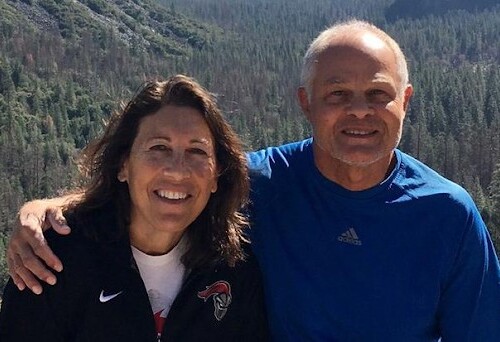 Two alumni in front of a mountain smiling at the camera.
