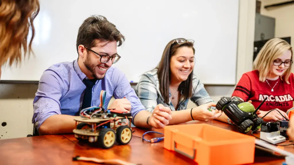 Students smiling while working on a robotic car.