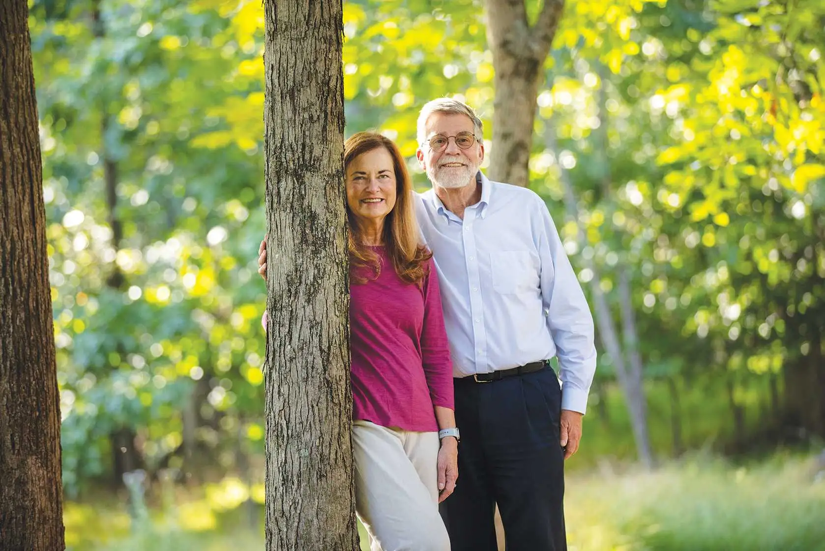 Alumni Weber family smiling at the camera while posing against a tree.