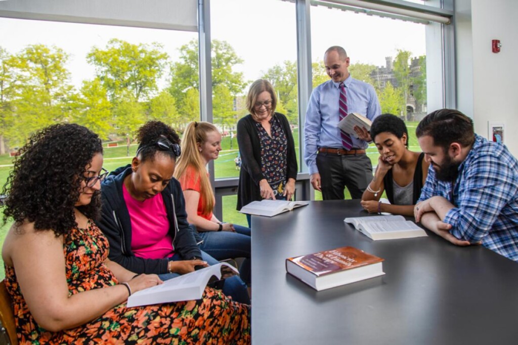 Counseling graduate students sit while meeting faculty in a large room.