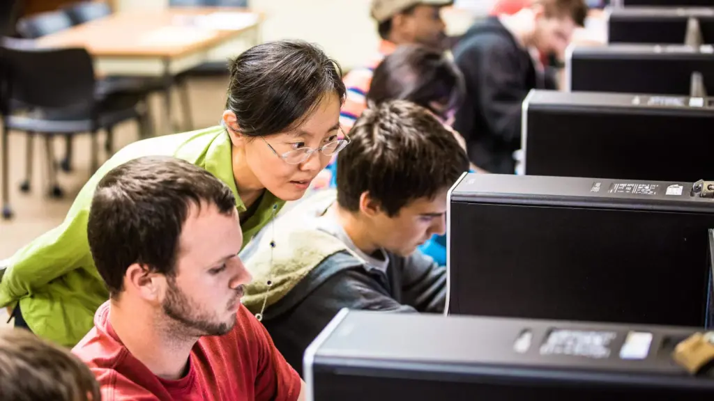 Yanxia Jia instructs students in a classroom filled with computers