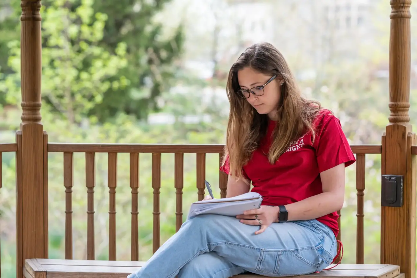 Student sits outside and writes in a notebook