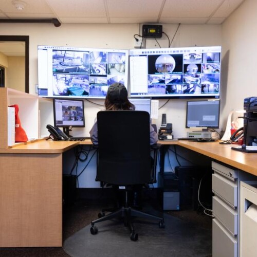 Department of Public Safety specialist at a computer with 5 monitors keeping the campus safe