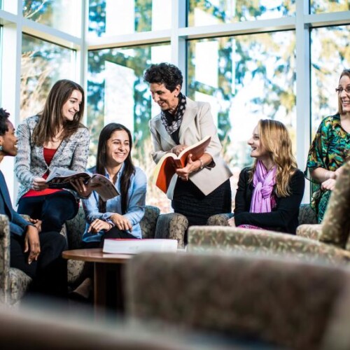 Six people, some with open books, communing in an indoor lounge area