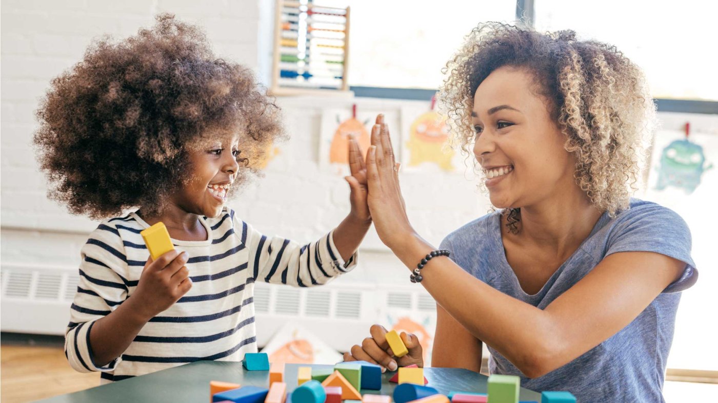 A woman and child giving each other a high-five while holding building blocks