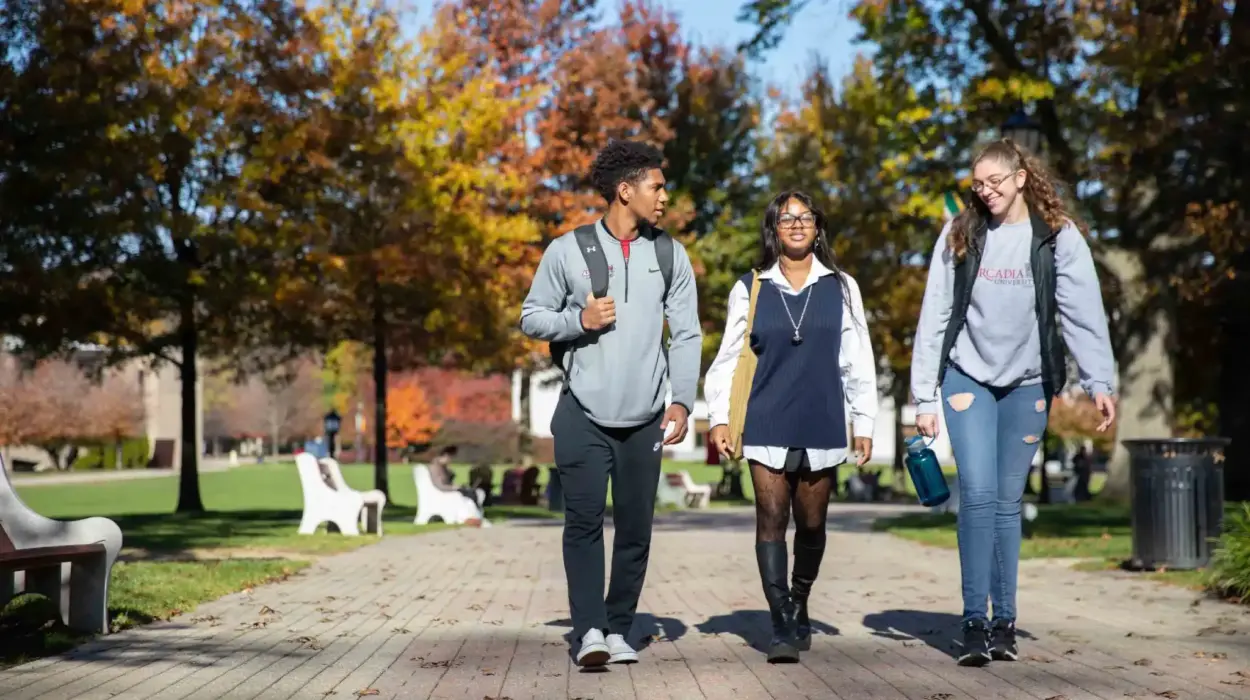 three students walking with eachother outside while smiling and talking to each other
