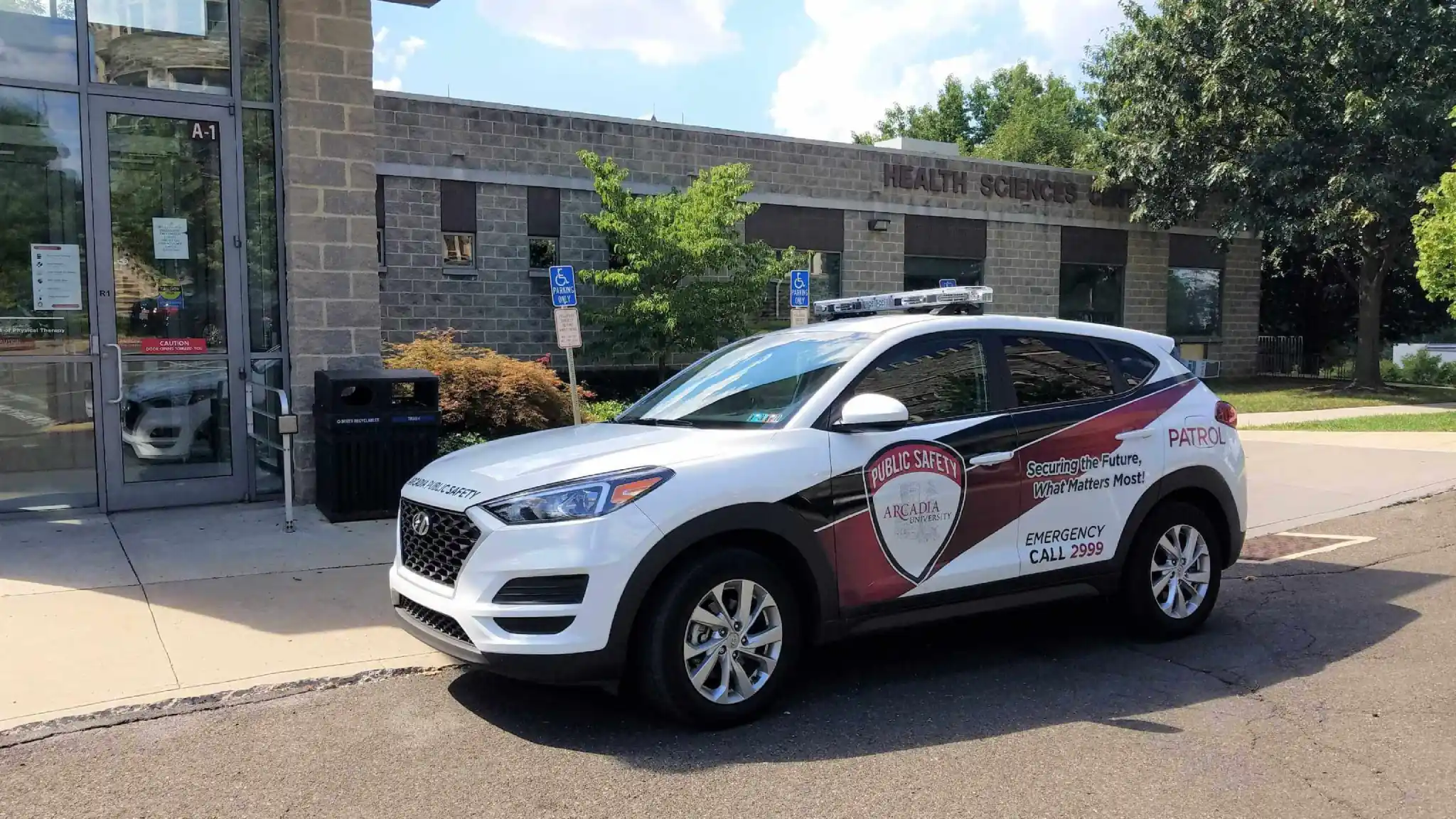 An Arcadia University Public Safety patrol car is parked next to a building on campus