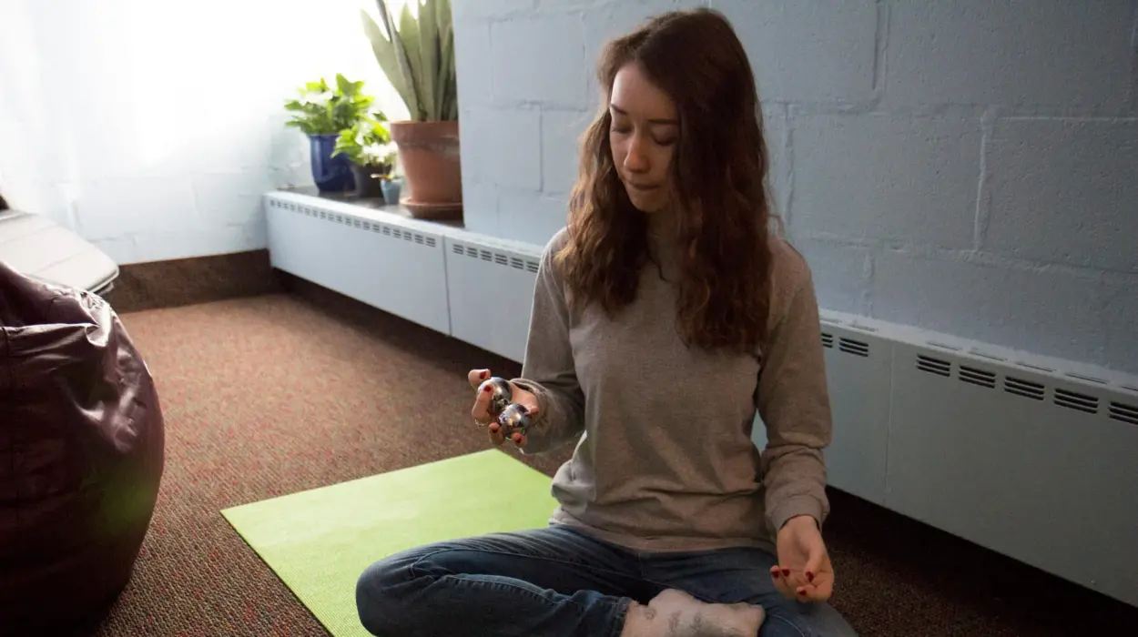 A student sits on a yoga mat in a meditative pose in the relaxation room