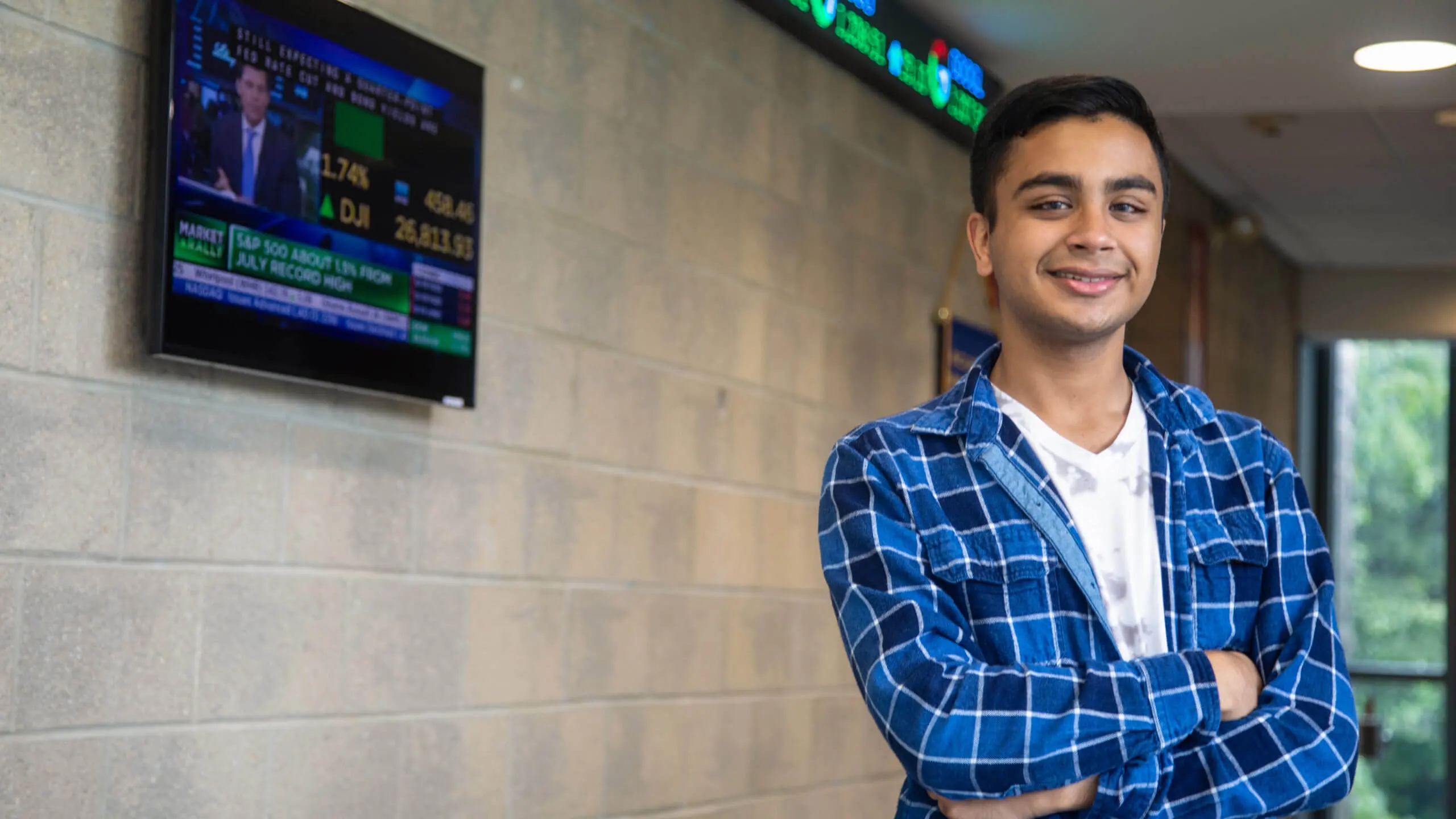 A business student stands in front of a stock ticker.