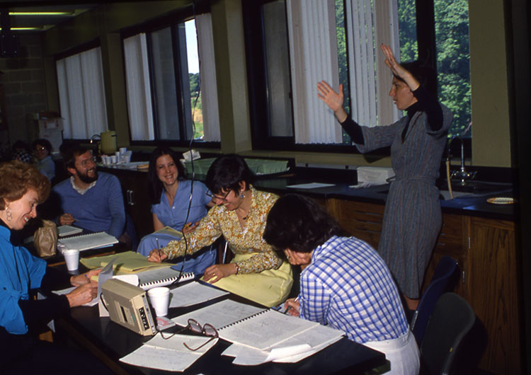 A professor talking to other professors in a classroom setting